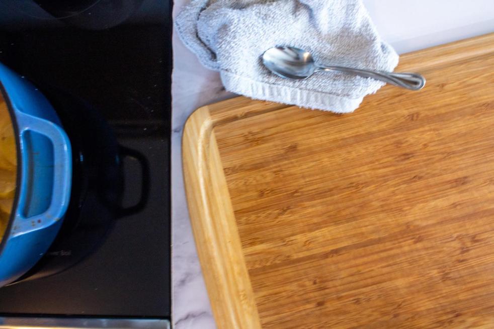 A wooden cutting board lays on a countertop after a woman learns how to deodorize a wooden cutting board.