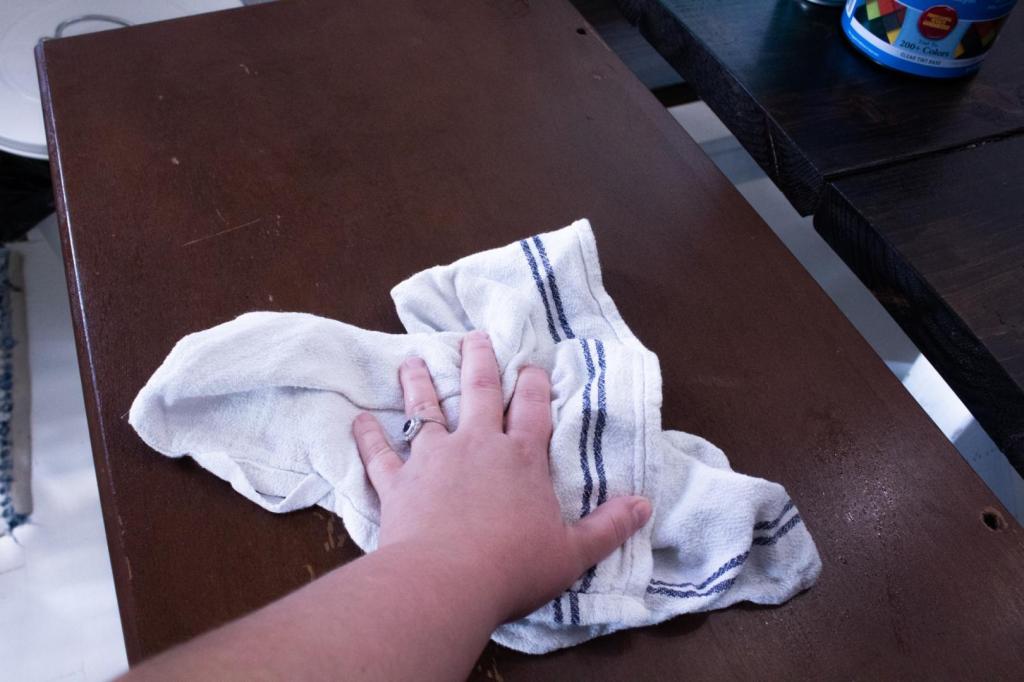 A woman wipes down a table as part of preparation for learning how to refinish wood furniture.