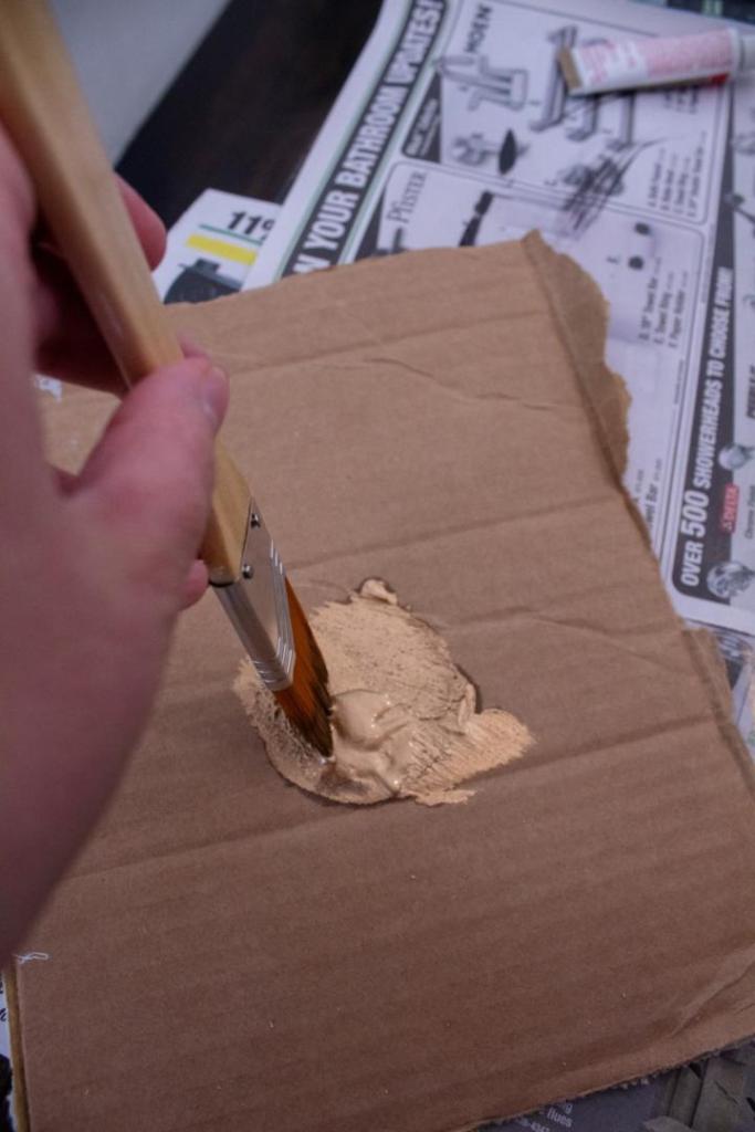 Gold paint is being lightly dipped into using a paint brush's tip.
