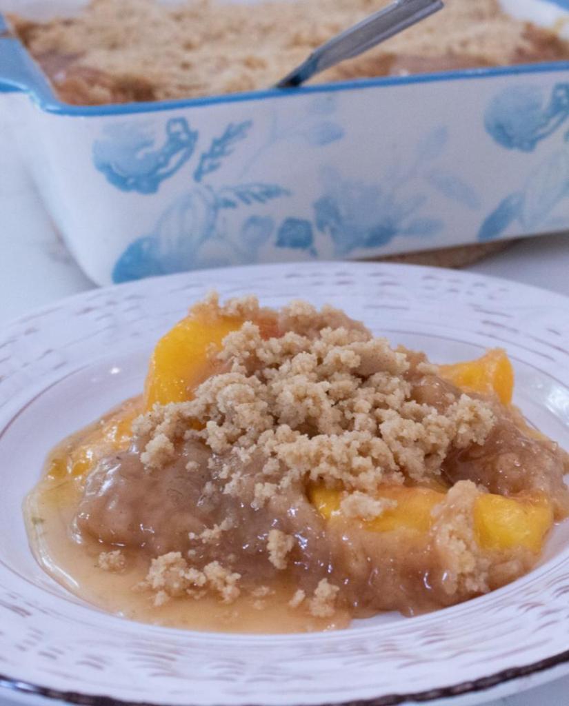 A peach crumble is plated onto a saucer.