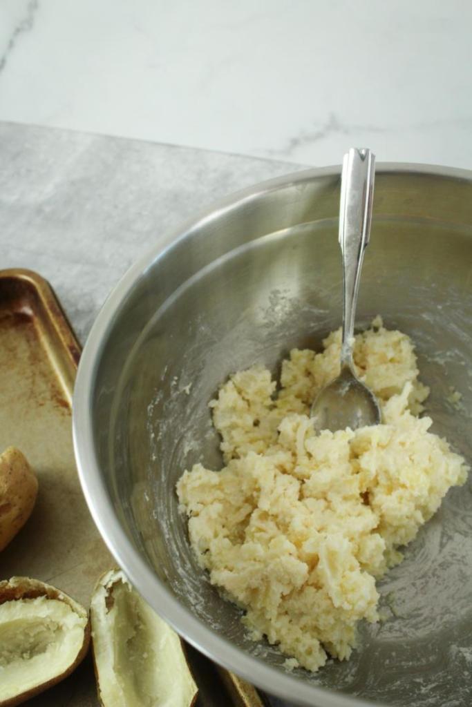 Potatoes have been mashed and mixed with various ingredients in a mixing bowl.