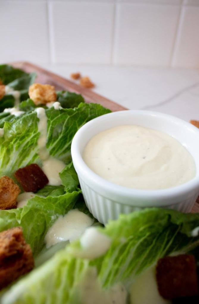 Salad dressing is served alongside a Caesar salad.