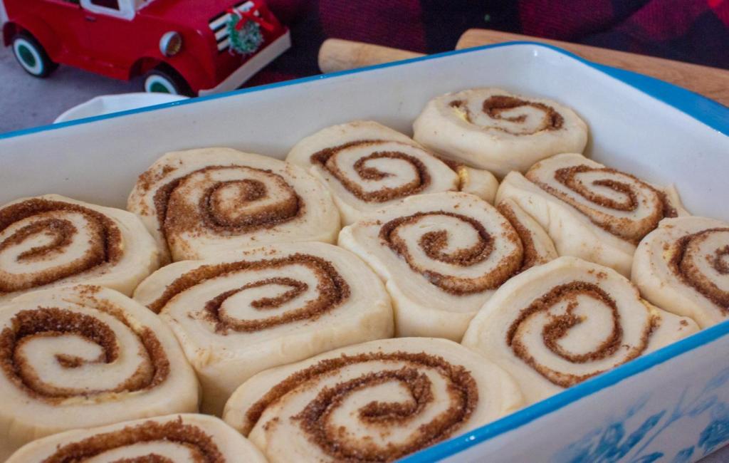 Cinnamon rolls, unbaked, are nestled into a casserole dish.