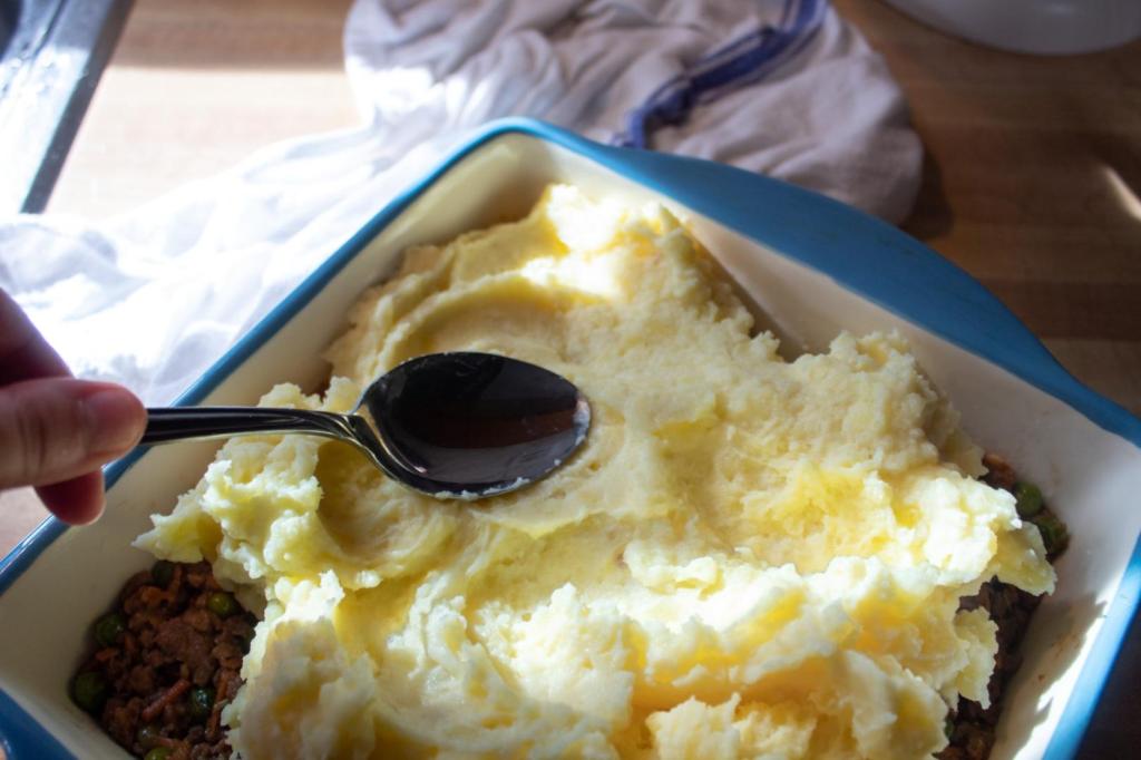 Mashed potatoes are spread in a dish.