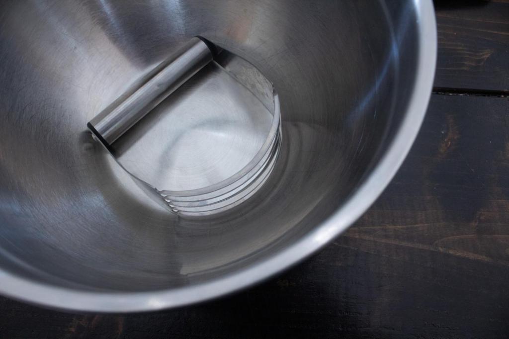 A large metal bowl has a pastry blender inside it before chilling.