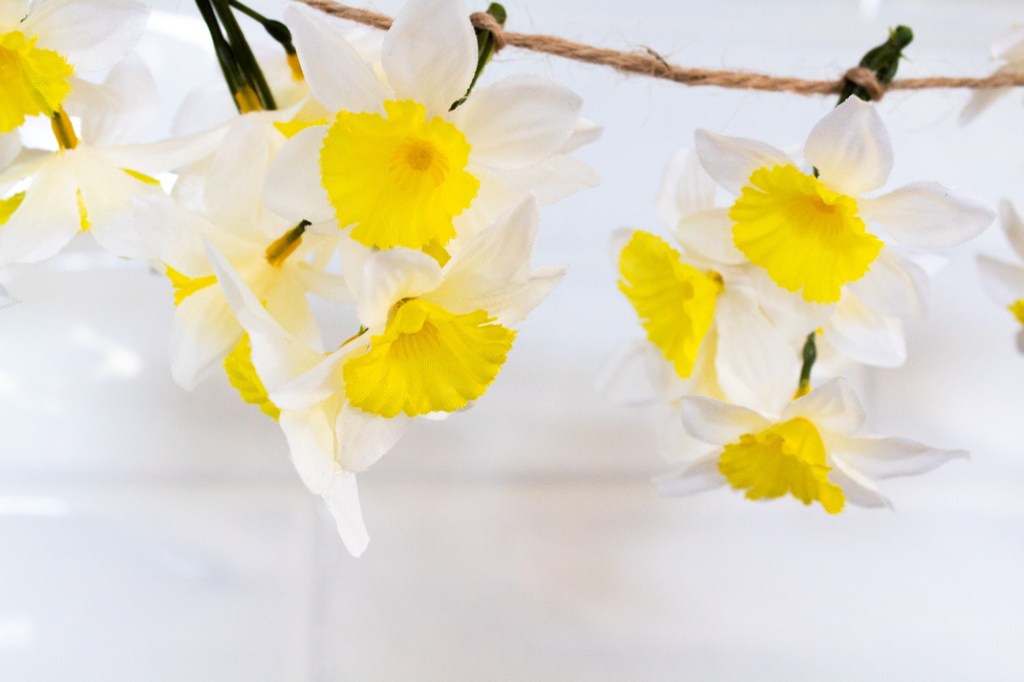 Faux daffodils are strung on a garland with twine.