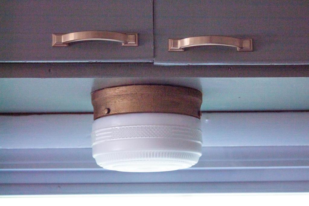 Rub n Buff on metal is shown on a vintage light fixture hanging above a sink.