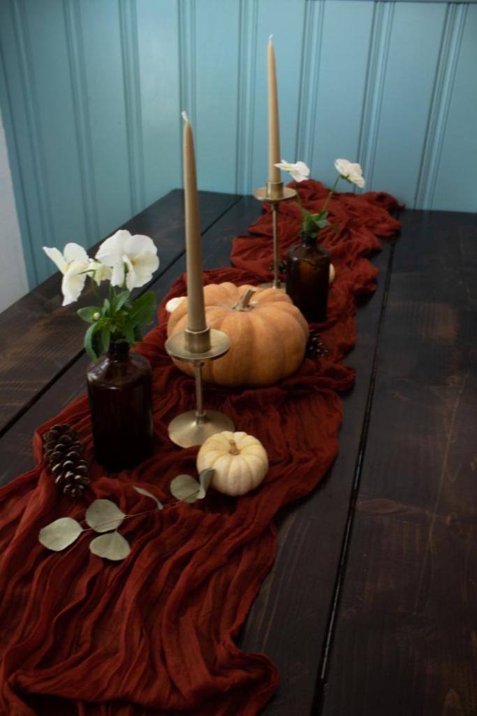 Candles add height to some fall table decor on a farmhouse table.