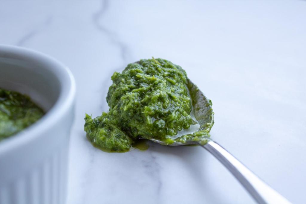 A spoon has a basil garlic pesto in it.