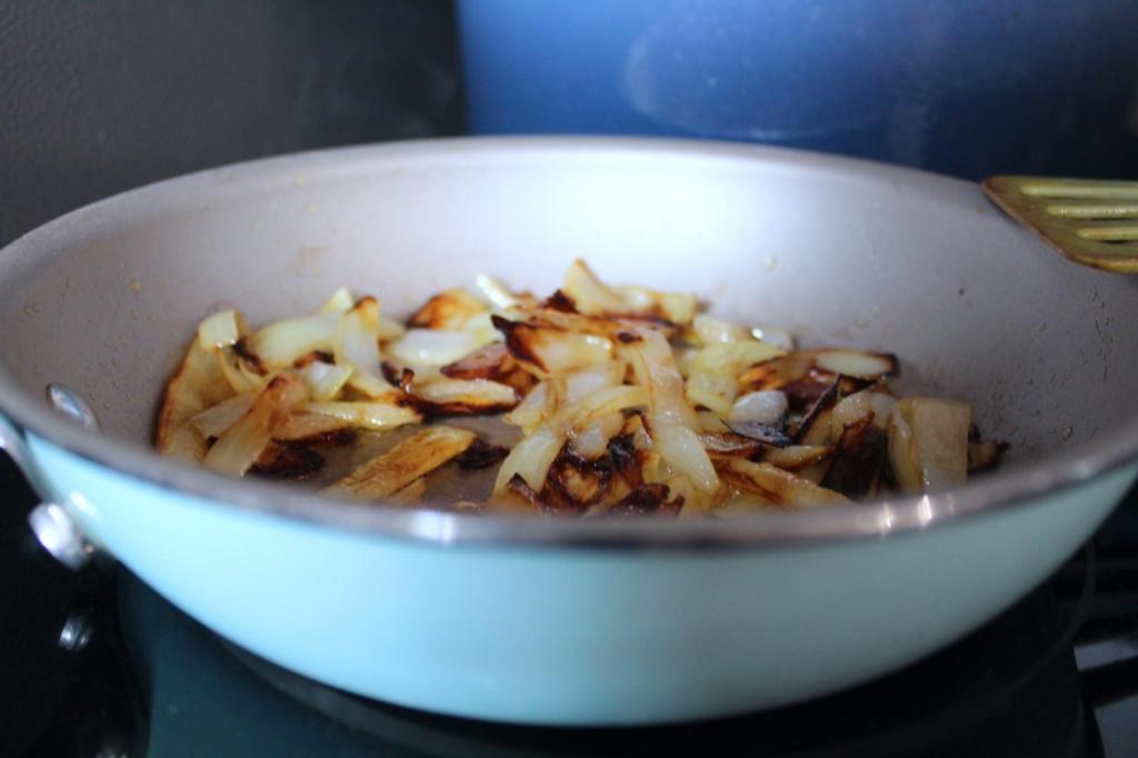 Caramelized onions sit in a skillet on a stovetop.