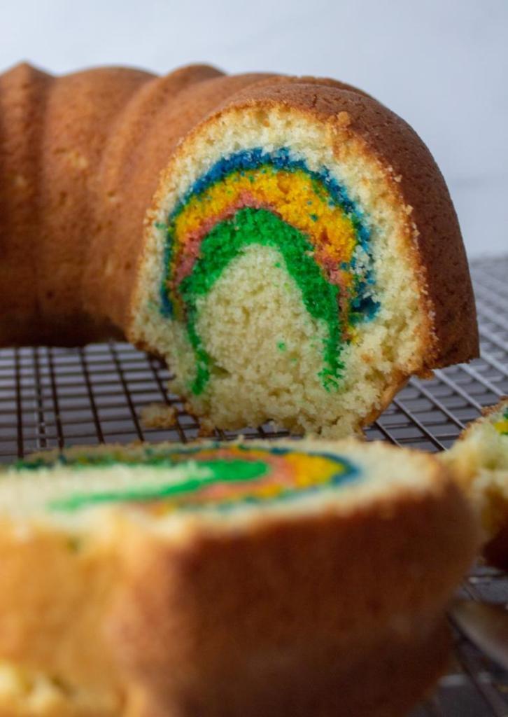 Rainbow colors shine through in a sliced rainbow bundt cake.