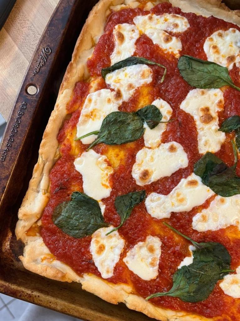 Authentic Italian Pizza is covered with spinach, marinara, and cheese.