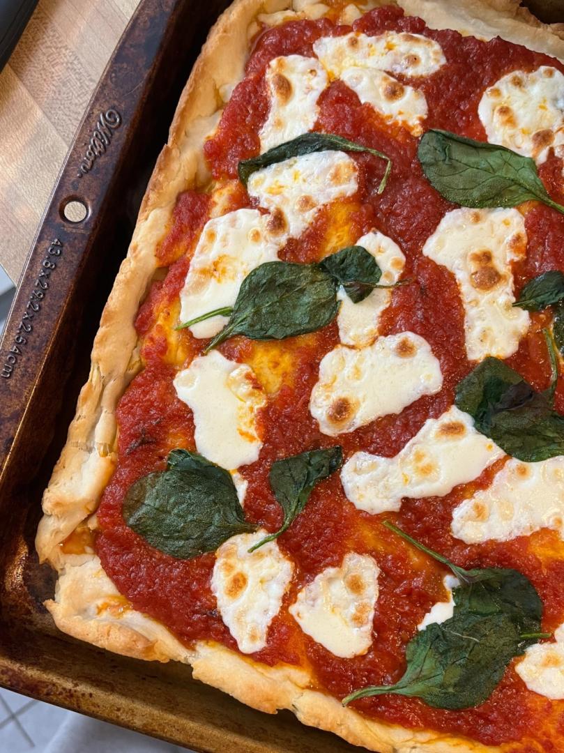 Authentic Italian Pizza is covered with spinach, marinara, and cheese.