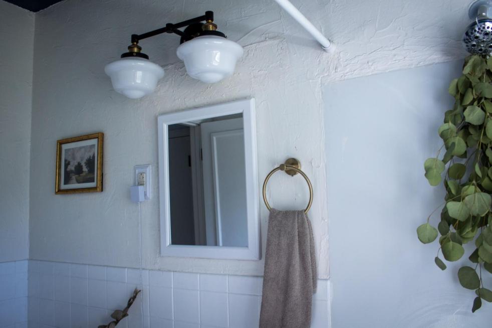 A mini cottage bathroom makeover happens after adding a new light fixture and hardware, along with new wall art, all pictured in this small pristine white bathroom.