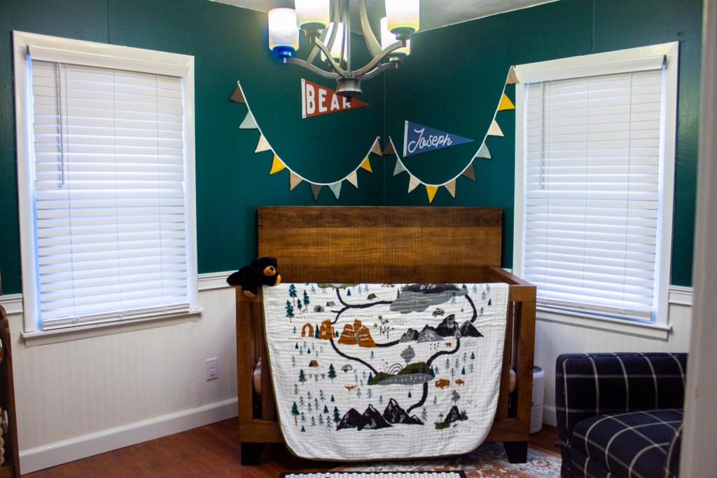 A crib has a national park quilt draped across it.