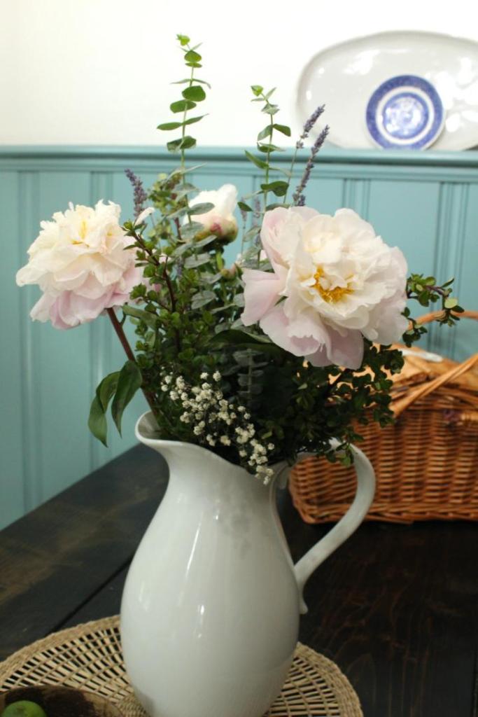 A flower arrangement sits in its place on a cottage dining table.