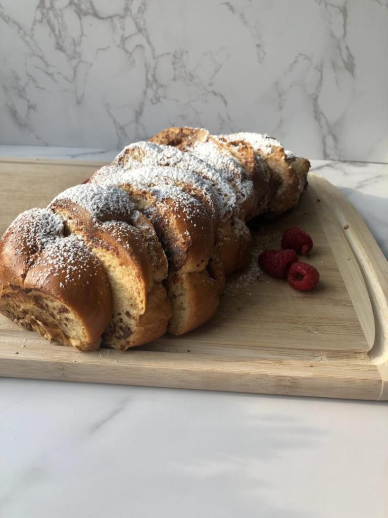 Challah French toast shines bight in the sunshine as it sits on a marble countertop next to a window.