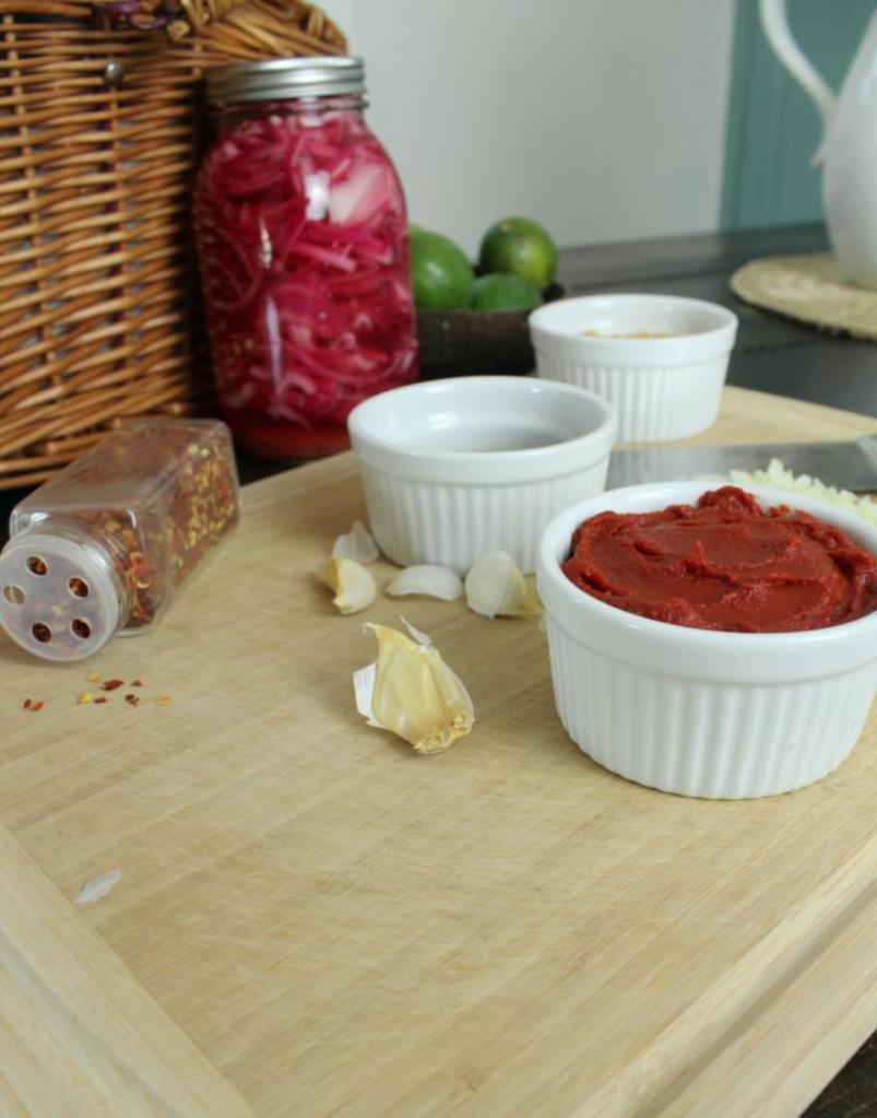 Several ingredients are scattered about a cutting board on a table.