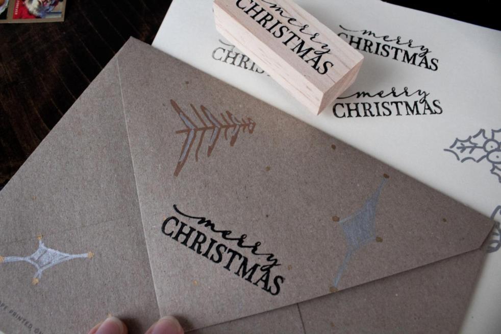 Christmas card envelope decorating ideas are shown with a Kraft envelope that has been drawn on with markers.