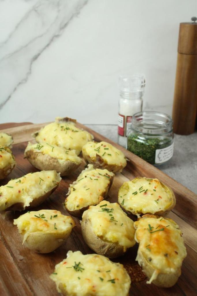 Easy twice baked potatoes are topped with cheese and chives and served up on a tray.