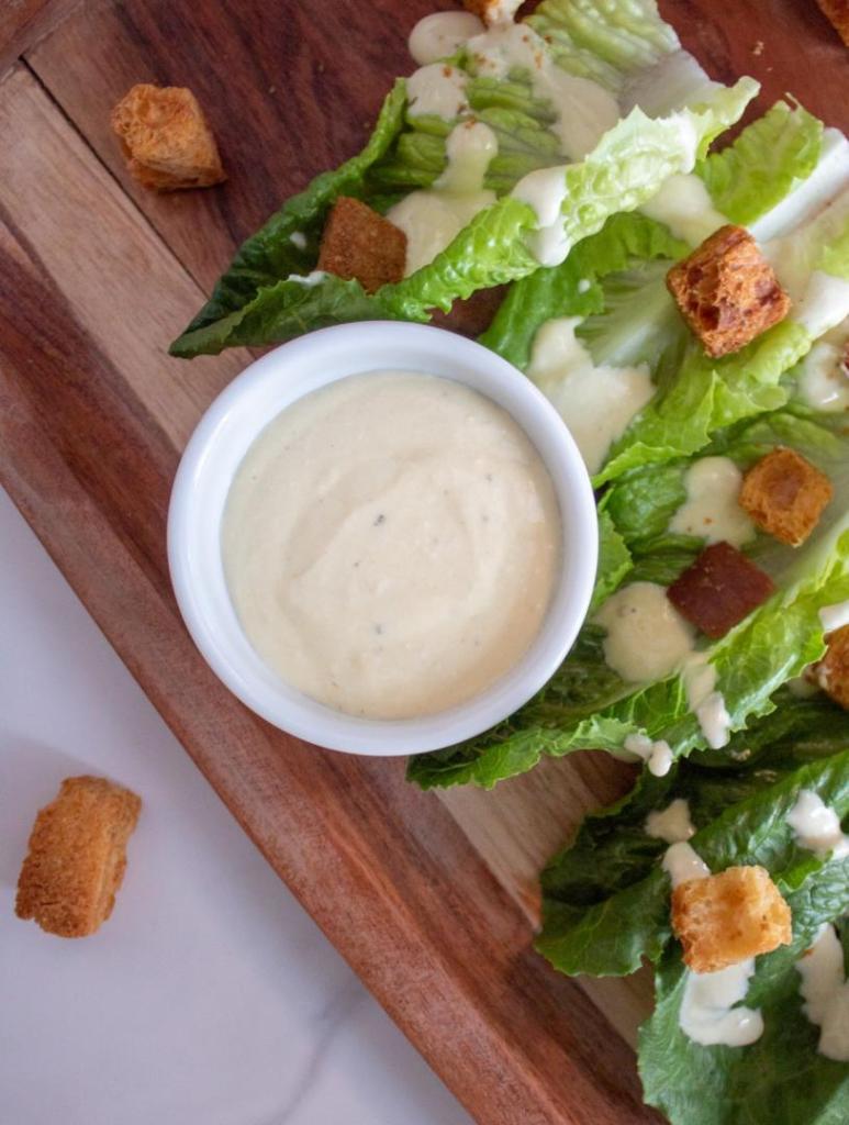 Caesar dressing is shown on a salad platter with greek yogurt among other ingredients.