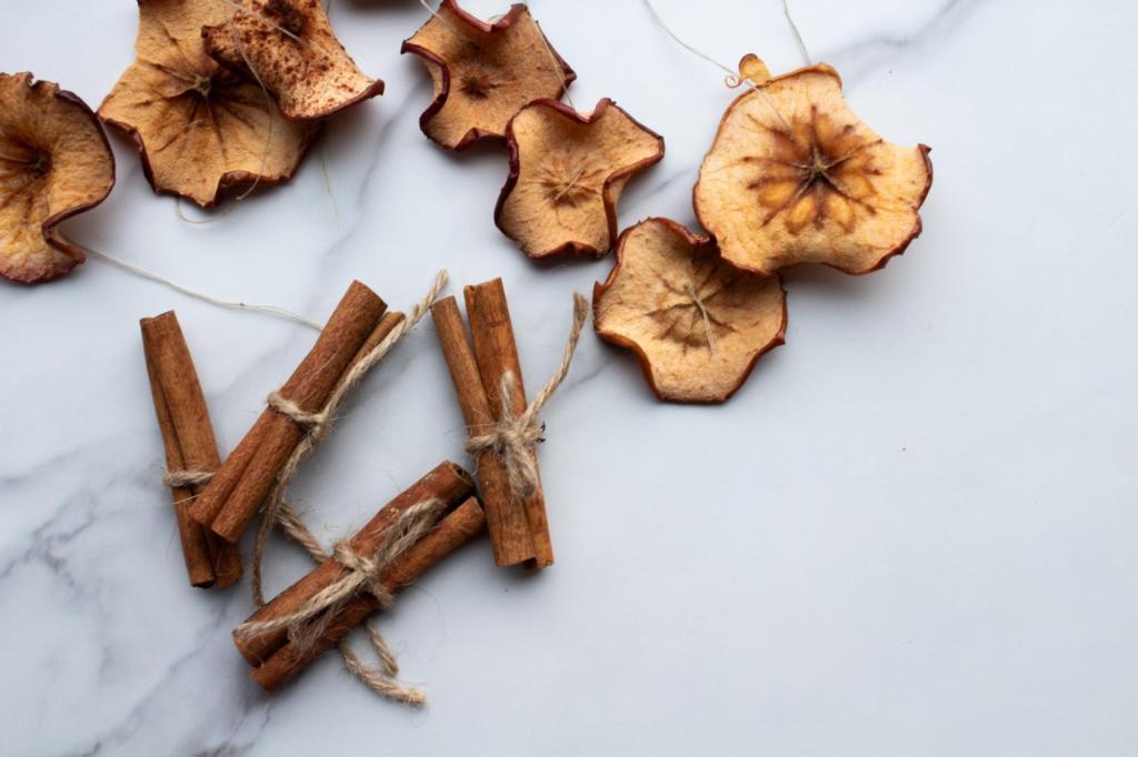Thread is strung through dried apples while cinnamon sticks are bundled together with twine to make "ornaments" for stringing on a garland later.
