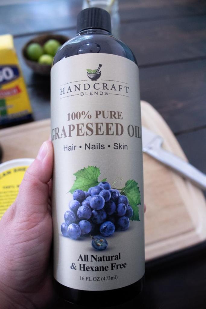A woman holds a bottle of grapeseed oil.