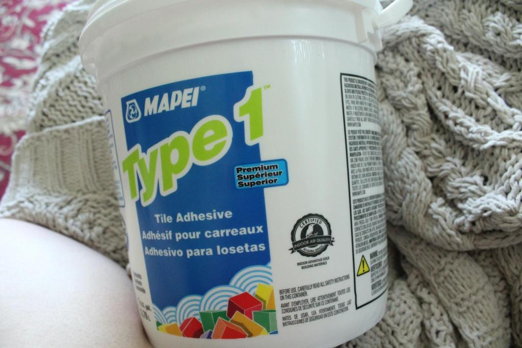 Tile adhesive sits in a bucket on a woman's lap.