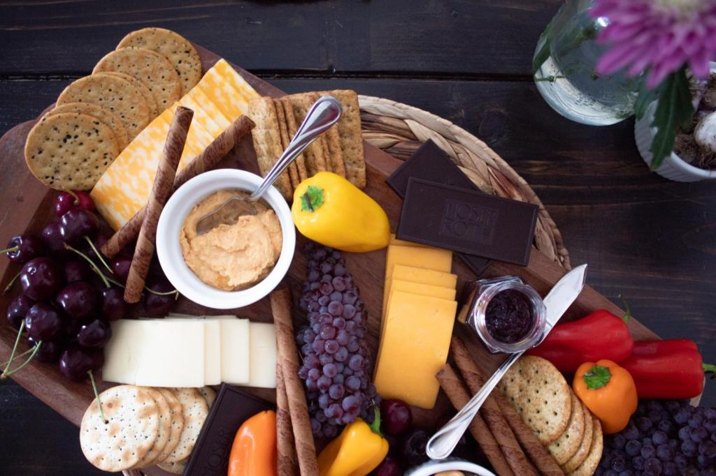 A vegetarian charcuterie board is placed next to flowers on a table.