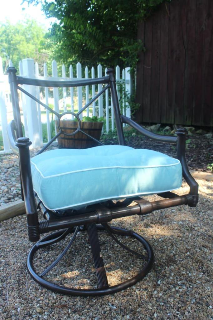 A metal patio chair has been refinished and looks shiny and fabulous on a pea gravel patio.