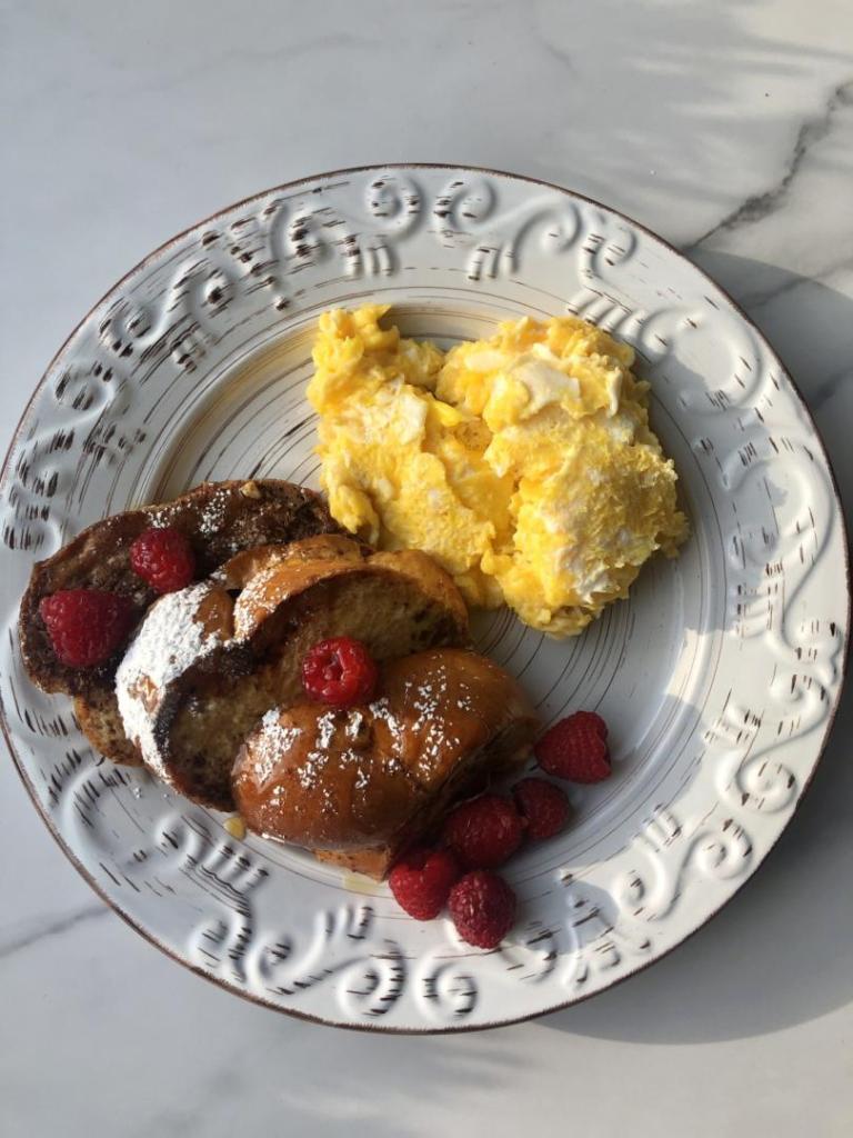A French toast recipe has loads of raspberries and is served with eggs.