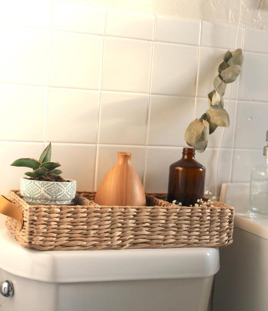 An essential oil diffuser sits behind a toilet and is essential on this bathroom cleaning checklist.