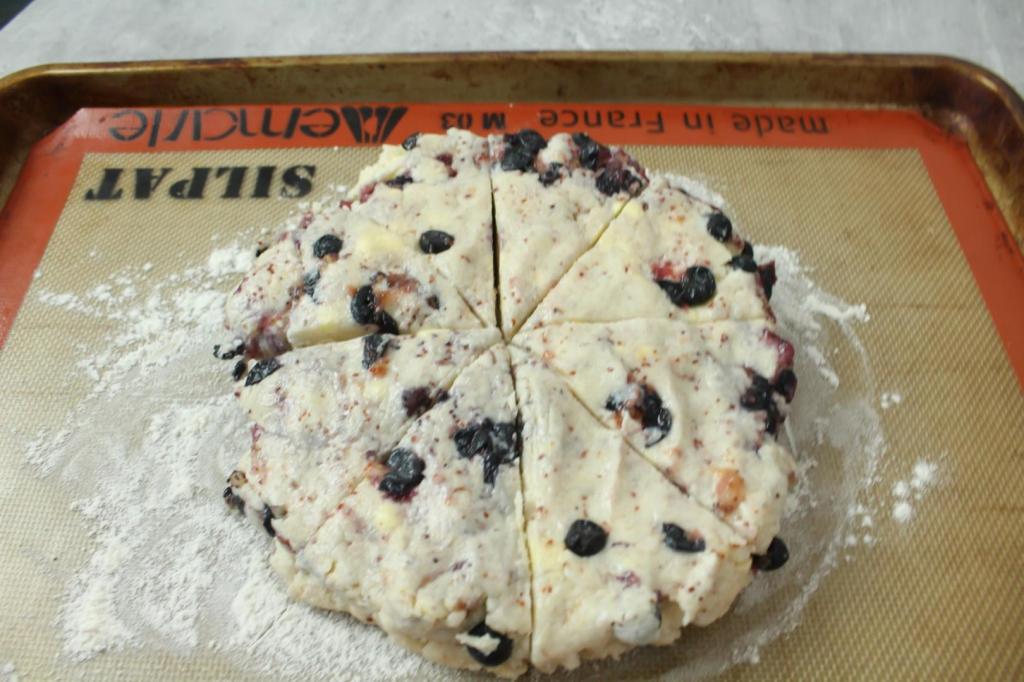 Lemon blueberry scones dough has been cut into 8 wedges.