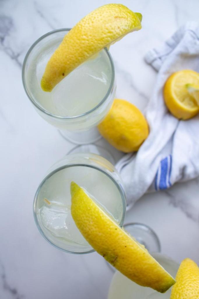 Glasses of lemonade have lemon wedges added to the rim.