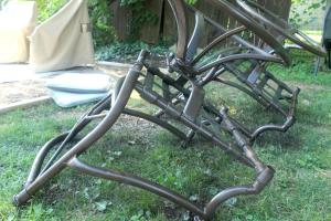 Patio furniture has its first coat of paint added to the underside of it. The chairs are upside down for this.