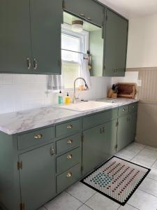 Kitchen cabinets have been painted a sage green color after learning how to paint kitchen cabinets without sanding.