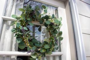 A lavender wreath DIY is hung outside a white door.