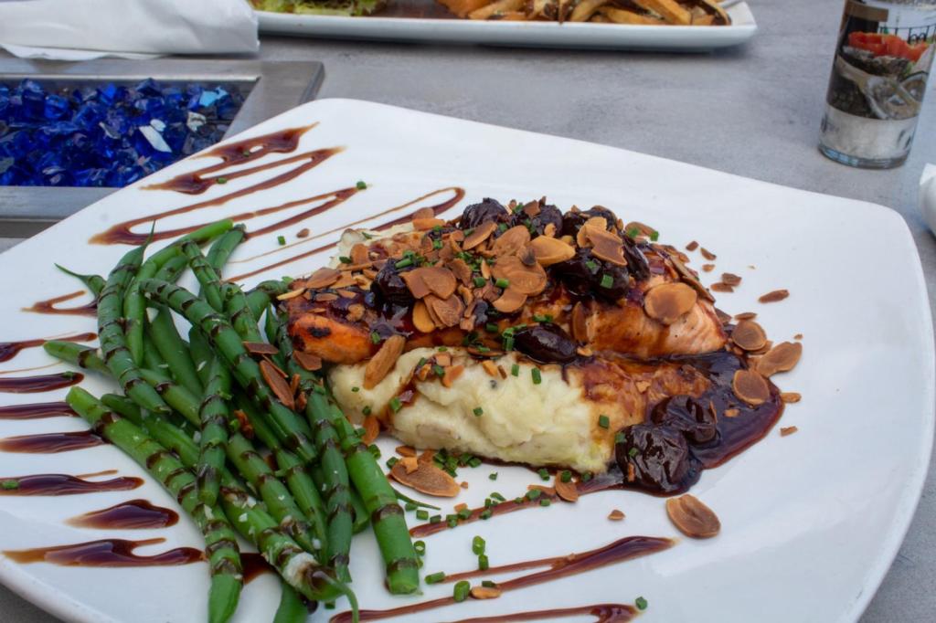 Salmon, mashed potatoes, and green beans are decorated on a plate.