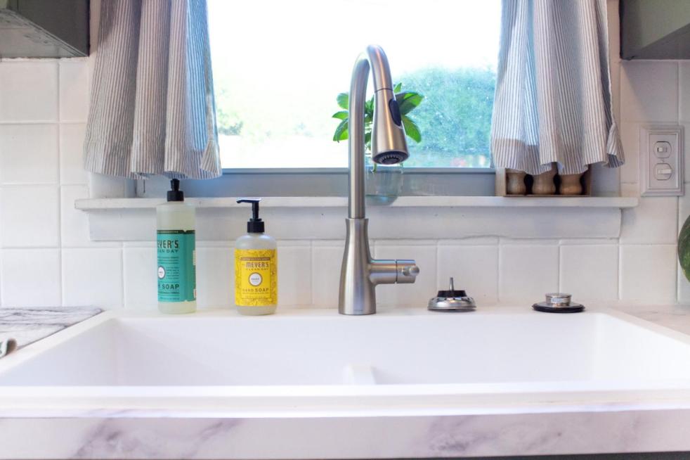 A white farmhouse sink is shown front and center in a post about how to clean a quartz sink.