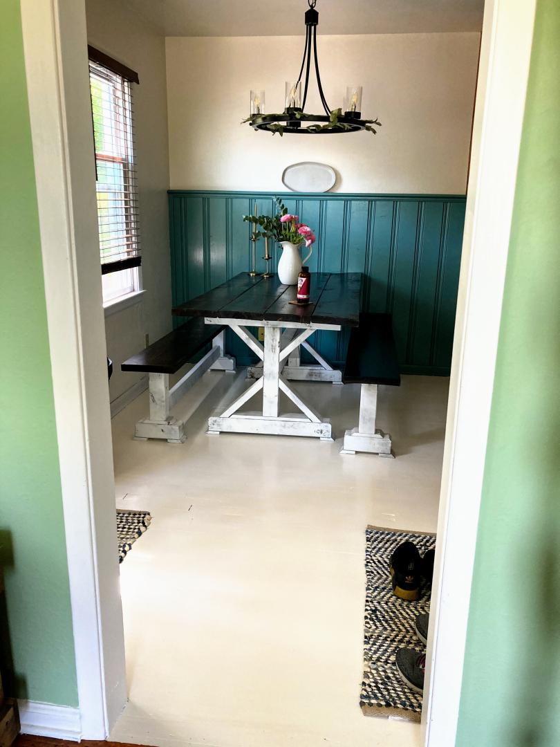 a walnut-stained dining table with benches and a pitcher of fresh flowers with cottage decor