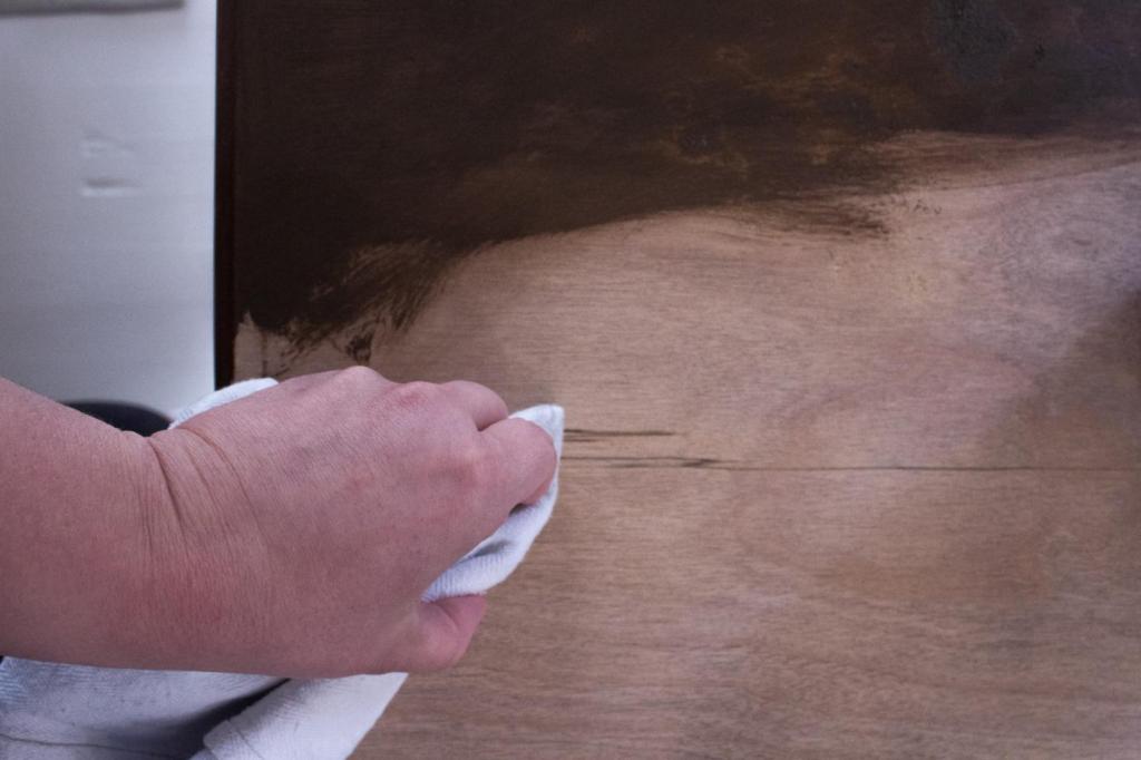 A woman applies stain to a table.