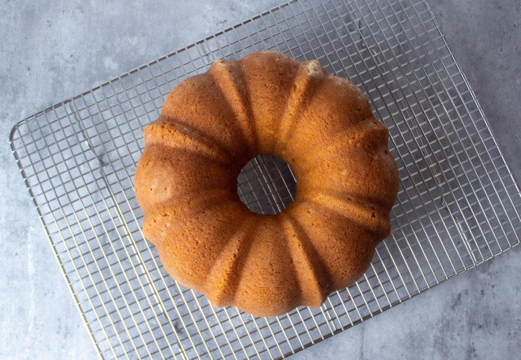 A bundt cake is inverted onto a cooling rack.