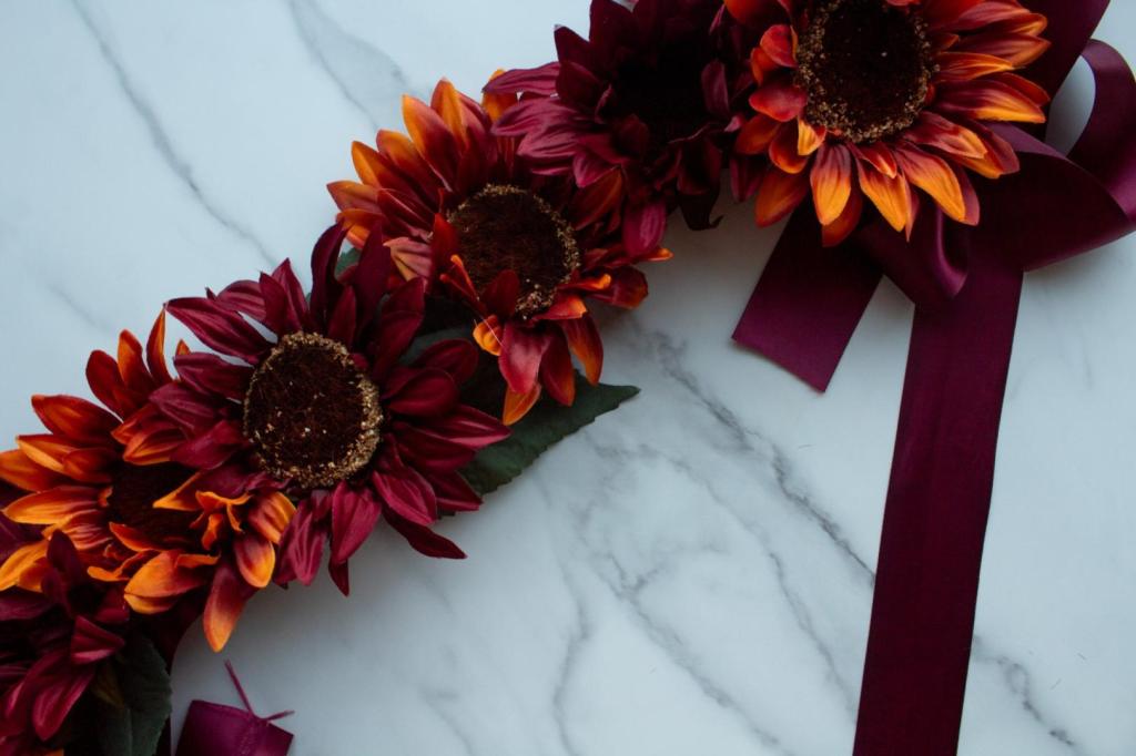 Sunflowers are lined up on a ribbon before hot gluing them on.
