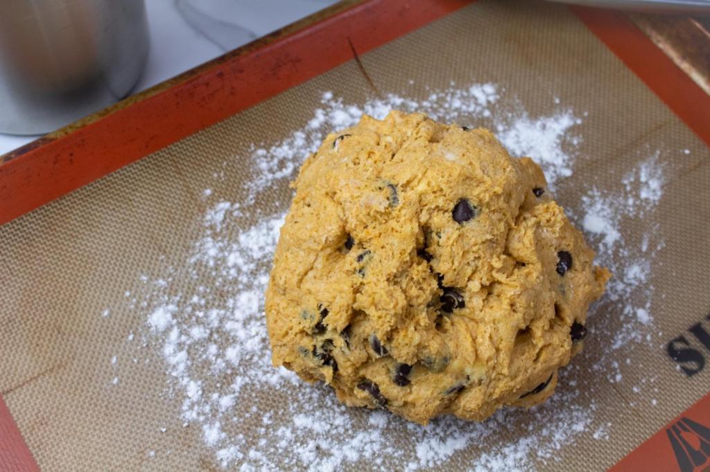 A scone mixture is balled up and placed on a baking mat.