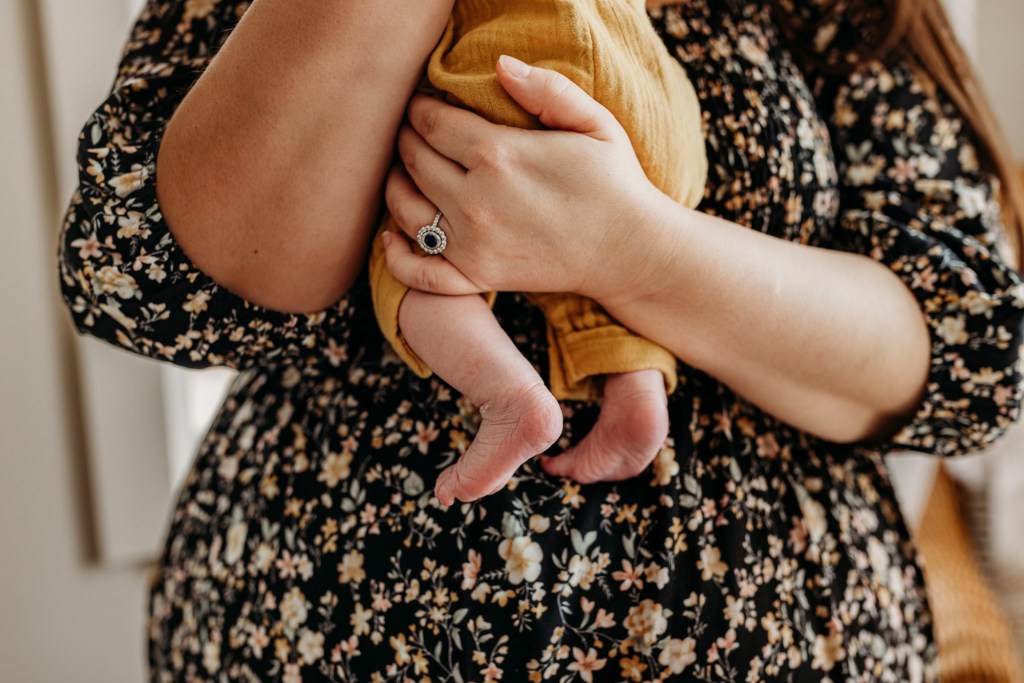 a woman holds a baby and his feet dangle
