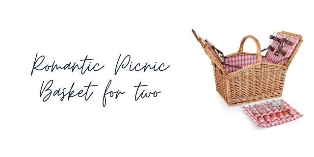 A cottagecore picnic basket is open and full of utensils and plates and glasses.