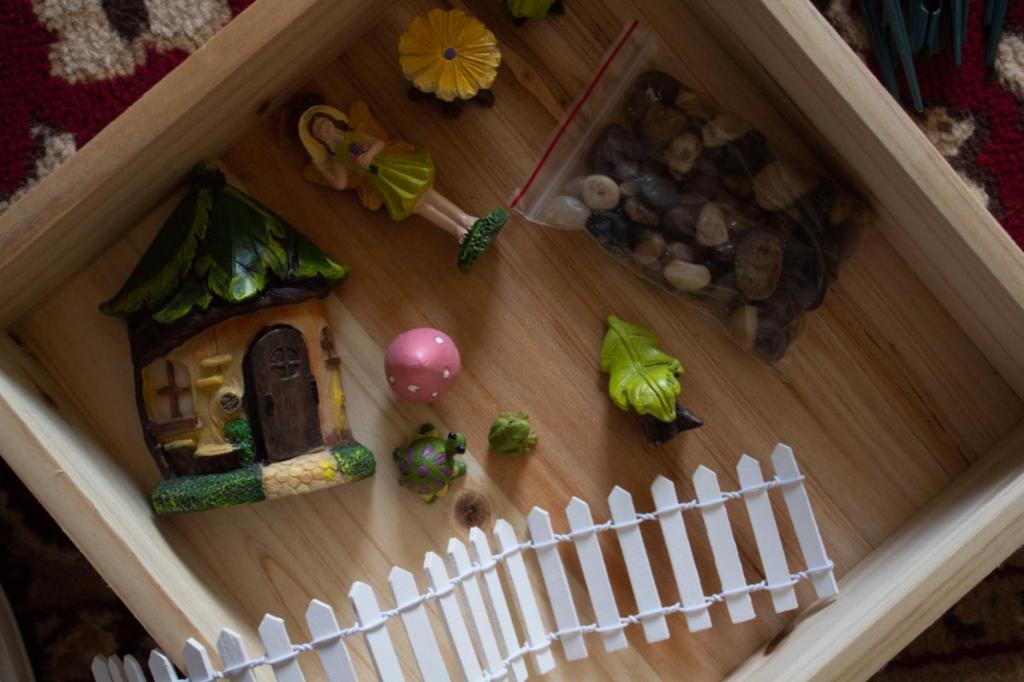 A DIY fairy garden has many pieces sitting inside an empty box, just waiting to be filled.