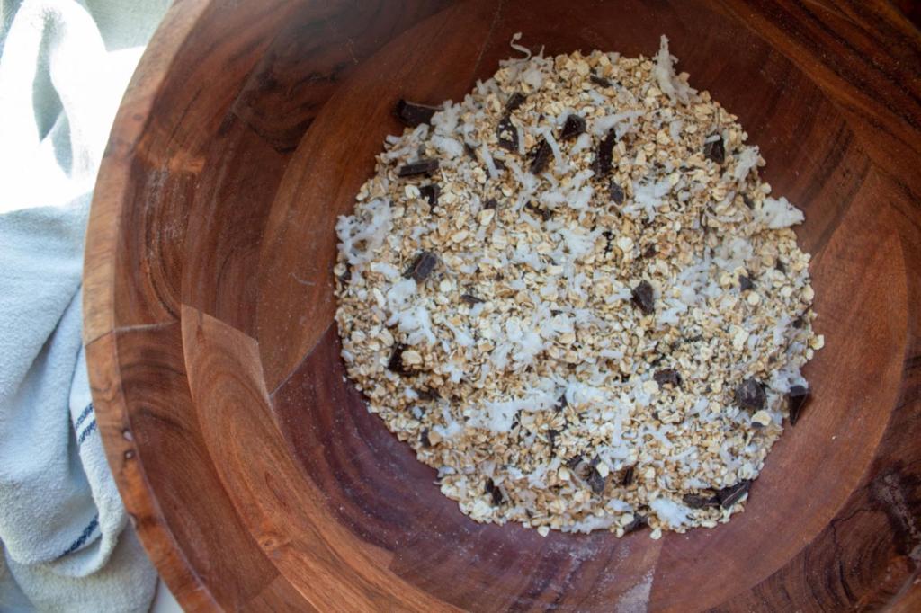 Dry ingredients are mixed into a large wooden bowl.