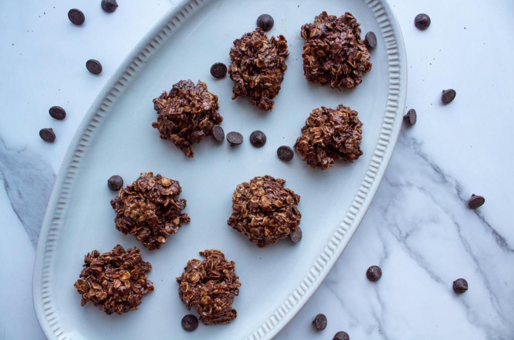 Chocolate oatmeal no bake cookies without peanut butter are photographed above an oval platter as they're scattered with chocolate chips.