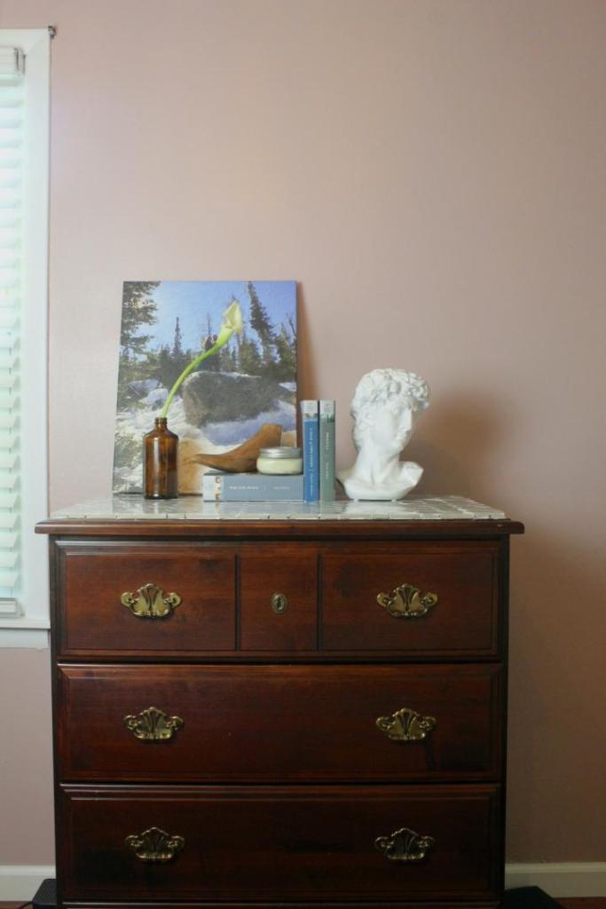 A DIY dresser makeover turned out perfectly with a marble top and newly decorated ambiance.